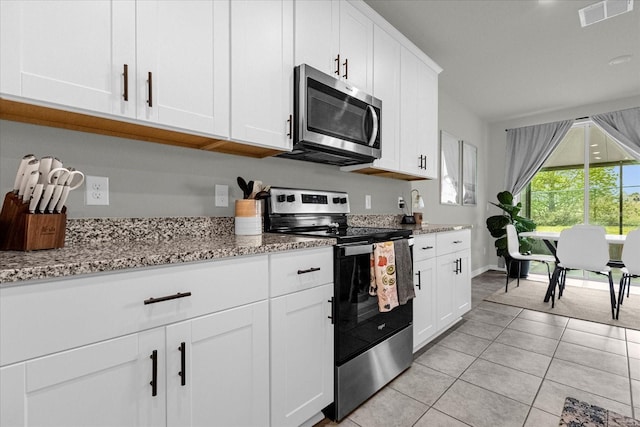 kitchen with stainless steel appliances, white cabinets, and light stone counters