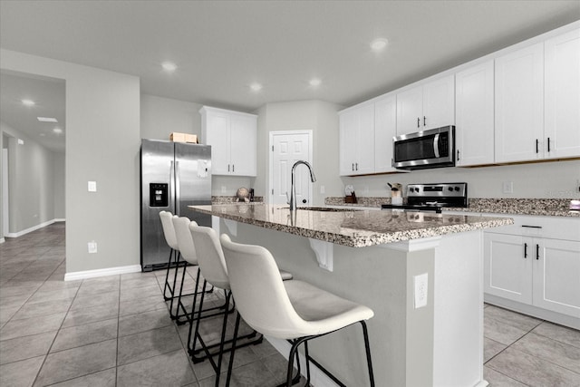 kitchen featuring a kitchen bar, sink, a center island with sink, and appliances with stainless steel finishes