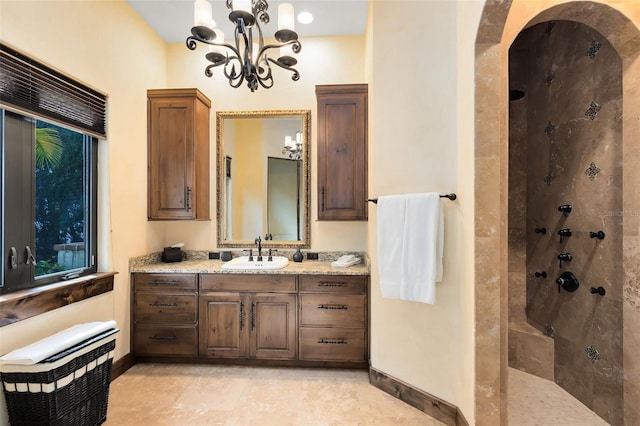 bathroom featuring vanity, tiled shower, and a notable chandelier