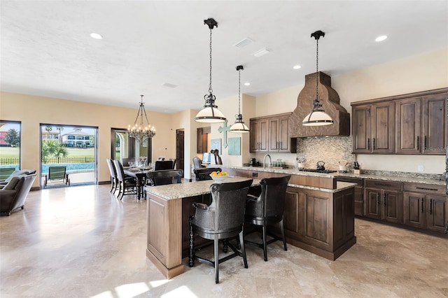 kitchen with light stone countertops, a center island, pendant lighting, and a kitchen bar