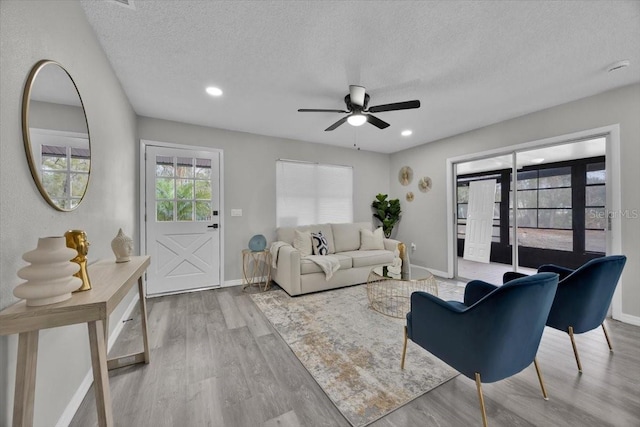 living room with ceiling fan, hardwood / wood-style floors, and a textured ceiling