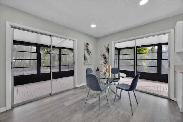 dining area with light hardwood / wood-style floors and a textured ceiling