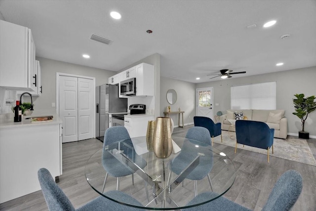 dining area with sink, light hardwood / wood-style flooring, and ceiling fan