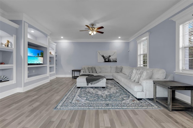 living room with hardwood / wood-style floors, crown molding, built in features, and ceiling fan