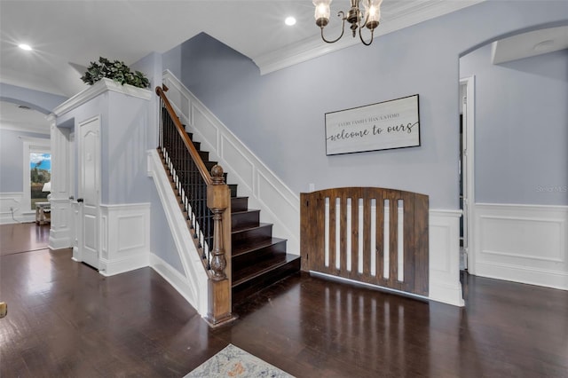 stairs featuring wood-type flooring, an inviting chandelier, and crown molding