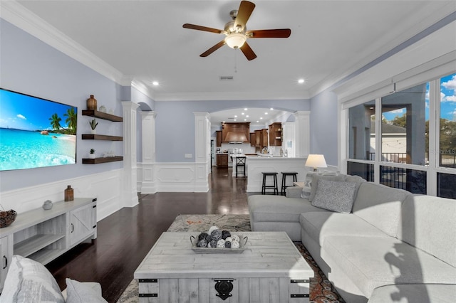 living room with crown molding, ceiling fan, dark hardwood / wood-style floors, and decorative columns