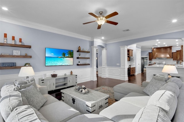 living room with crown molding, decorative columns, dark hardwood / wood-style floors, and ceiling fan