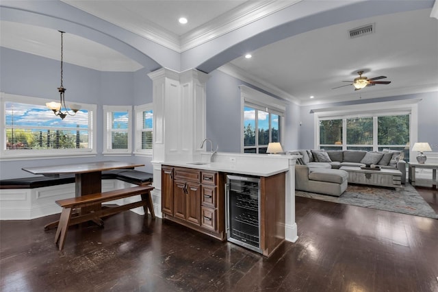 bar featuring sink, decorative light fixtures, ornamental molding, dark hardwood / wood-style flooring, and beverage cooler