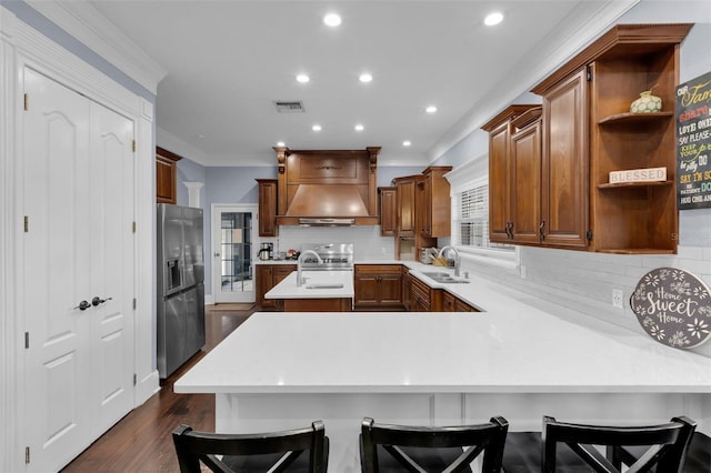 kitchen with sink, stainless steel fridge, a kitchen breakfast bar, ornamental molding, and kitchen peninsula