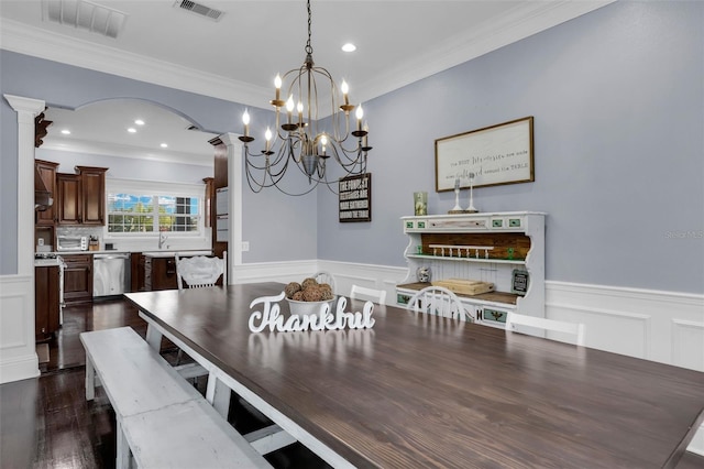 dining space with ornate columns, crown molding, dark wood-type flooring, and sink