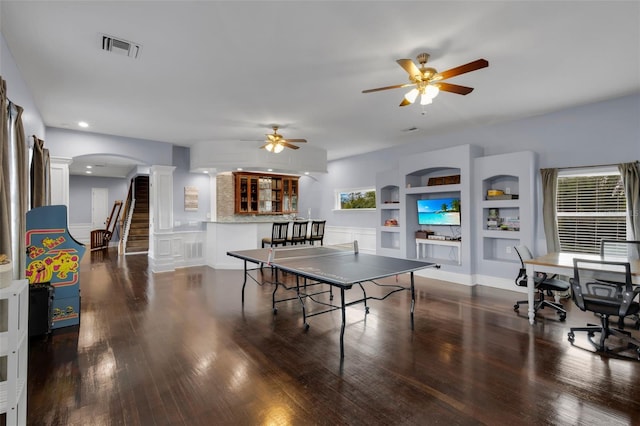 recreation room with built in shelves, dark wood-type flooring, decorative columns, and ceiling fan