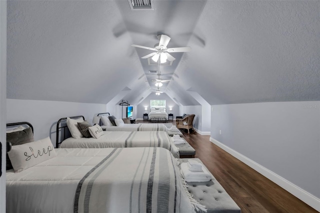 bedroom featuring ceiling fan, dark hardwood / wood-style flooring, vaulted ceiling, and a textured ceiling