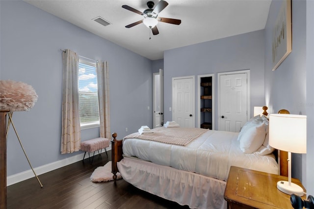 bedroom featuring dark hardwood / wood-style floors, two closets, and ceiling fan