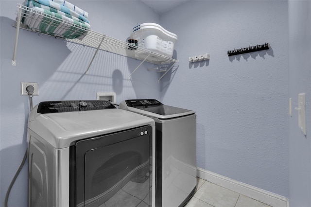 clothes washing area featuring light tile patterned flooring and separate washer and dryer