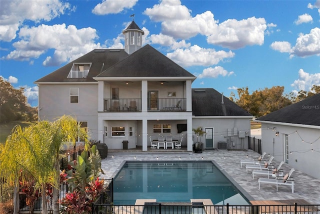 rear view of house featuring a fenced in pool, a balcony, cooling unit, and a patio area