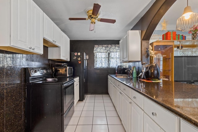 kitchen featuring black appliances, hanging light fixtures, dark stone countertops, light tile patterned floors, and white cabinets