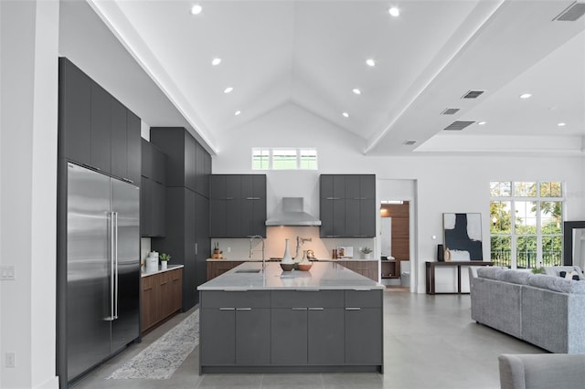 kitchen with built in fridge, high vaulted ceiling, a spacious island, backsplash, and wall chimney exhaust hood