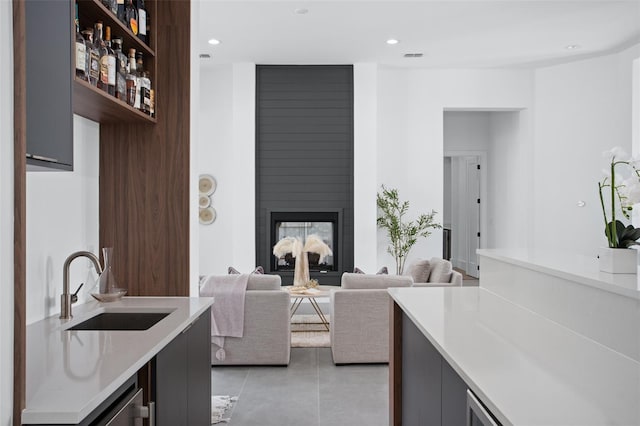 tiled living room with a multi sided fireplace and sink