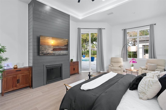 bedroom featuring multiple windows, a fireplace, access to exterior, and light wood-type flooring