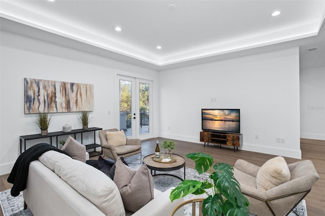 living room with french doors, a raised ceiling, and hardwood / wood-style floors