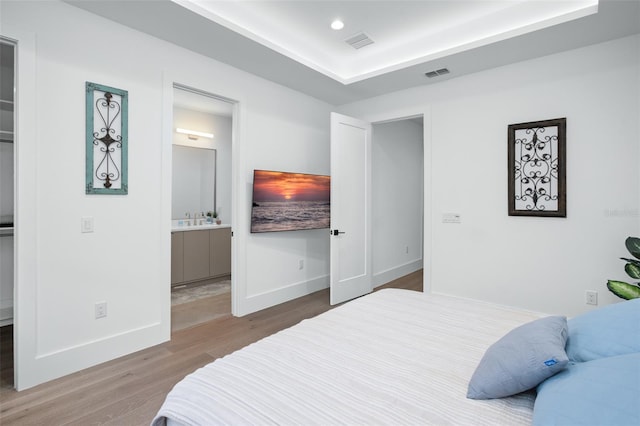 bedroom with sink, a spacious closet, hardwood / wood-style floors, and ensuite bath