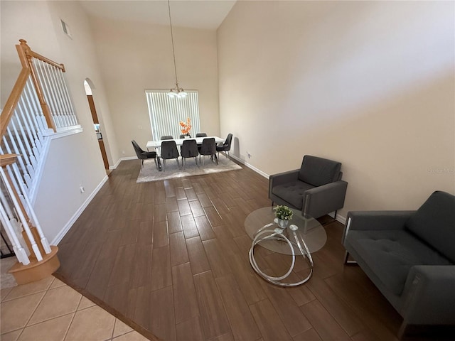 sitting room with a notable chandelier, hardwood / wood-style flooring, and a towering ceiling