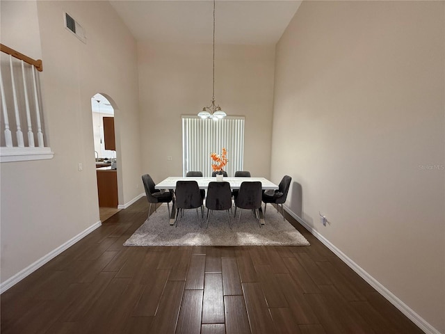 dining room featuring a towering ceiling, dark hardwood / wood-style flooring, and a chandelier