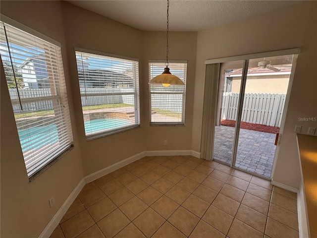 unfurnished dining area featuring light tile patterned floors, a textured ceiling, and a healthy amount of sunlight