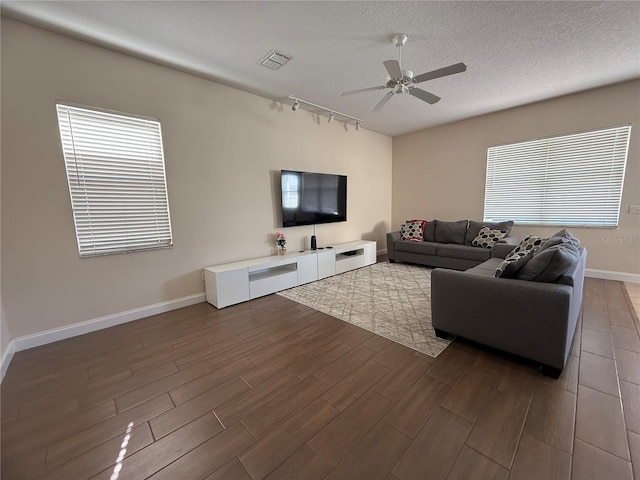 living room with rail lighting, dark hardwood / wood-style floors, ceiling fan, and a textured ceiling