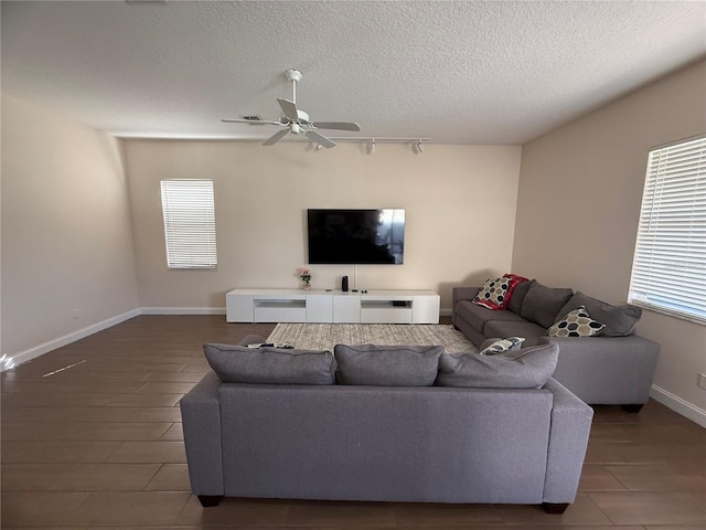 living room with dark hardwood / wood-style flooring, plenty of natural light, a textured ceiling, and ceiling fan