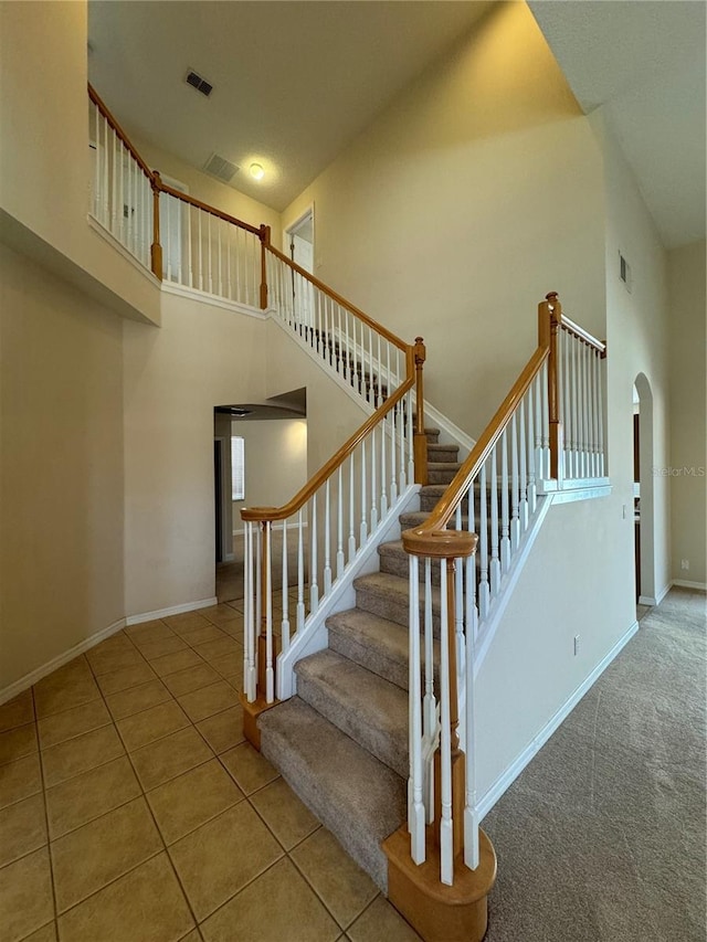 stairs featuring a high ceiling and tile patterned flooring