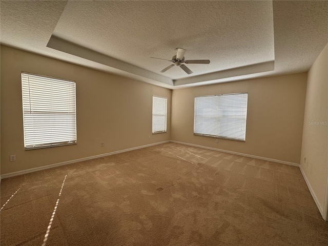 carpeted spare room with ceiling fan, a tray ceiling, and a textured ceiling