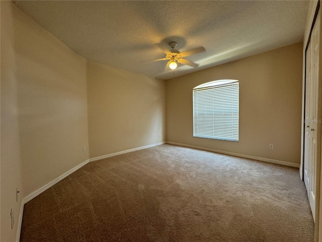 empty room featuring ceiling fan, carpet floors, and a textured ceiling