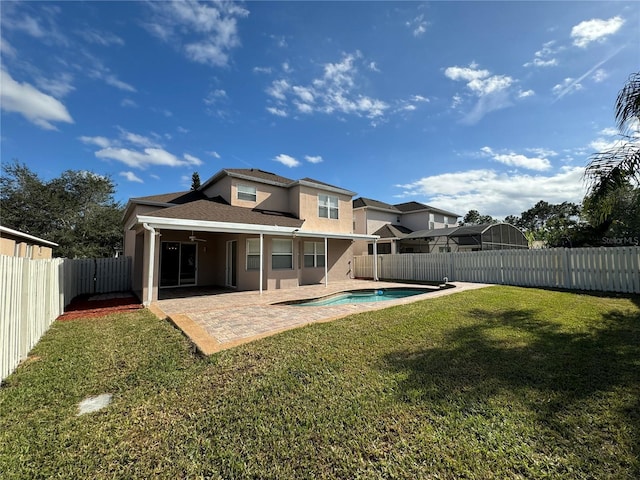 rear view of property featuring a fenced in pool, a lawn, and a patio