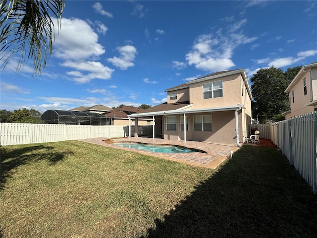 rear view of house featuring a yard, a fenced in pool, and a patio area