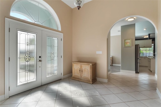 entryway featuring light tile patterned floors, french doors, and a high ceiling