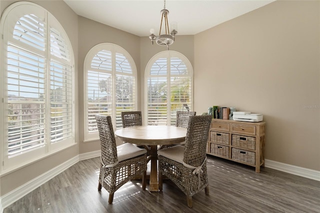 dining space with an inviting chandelier, baseboards, and wood finished floors