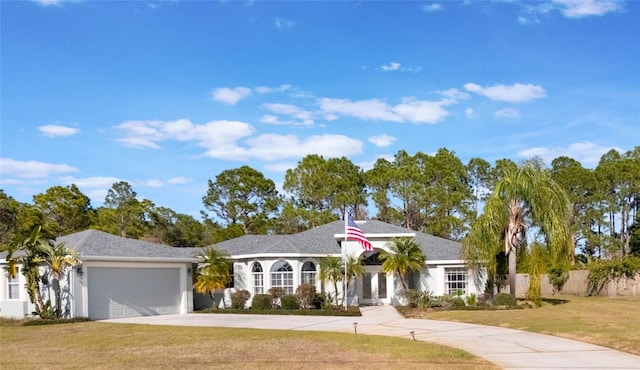 view of front facade with stucco siding, an attached garage, fence, driveway, and a front lawn