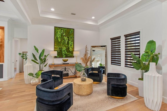 living area featuring ornamental molding, a raised ceiling, and light wood-type flooring