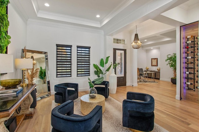 living room with crown molding, light hardwood / wood-style floors, and a raised ceiling