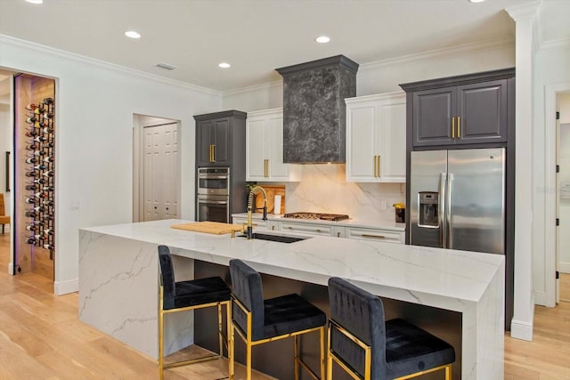 kitchen with a large island with sink, white cabinetry, appliances with stainless steel finishes, and sink