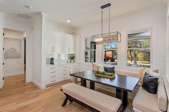 dining space with crown molding and light hardwood / wood-style flooring