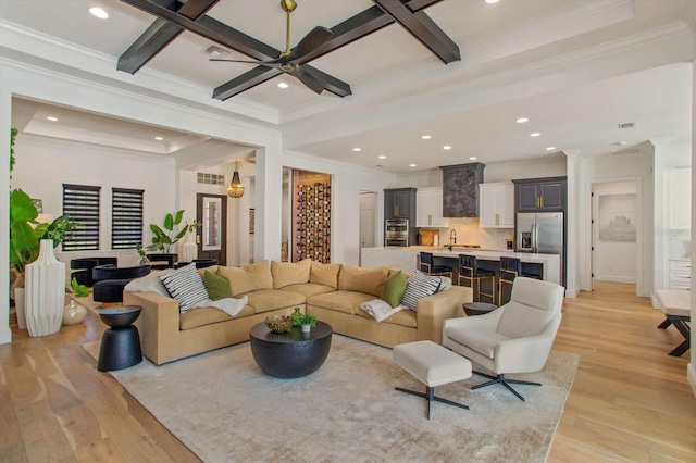 living room featuring ornamental molding, sink, ceiling fan, and light wood-type flooring