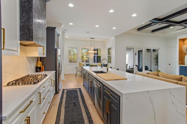 kitchen with sink, white cabinets, hanging light fixtures, stainless steel appliances, and light stone countertops