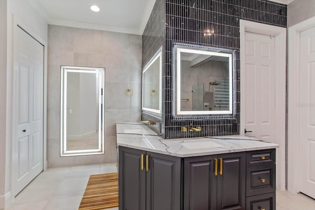 bathroom with tile patterned floors, ornamental molding, tile walls, and vanity