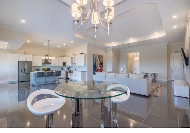 dining room with crown molding, a tray ceiling, a chandelier, and dark tile patterned floors