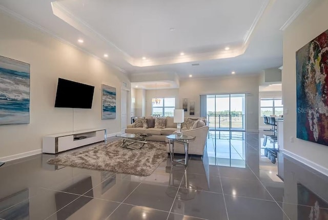 living room featuring dark tile patterned flooring, a tray ceiling, and ornamental molding