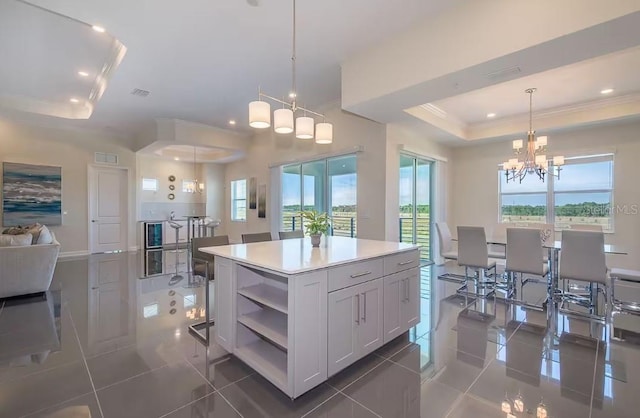 kitchen with a center island, hanging light fixtures, a tray ceiling, a notable chandelier, and white cabinets