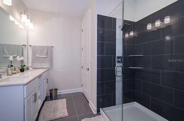 bathroom with a shower with door, vanity, and tile patterned flooring