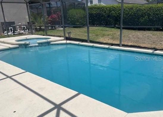 view of swimming pool featuring an in ground hot tub and a lanai